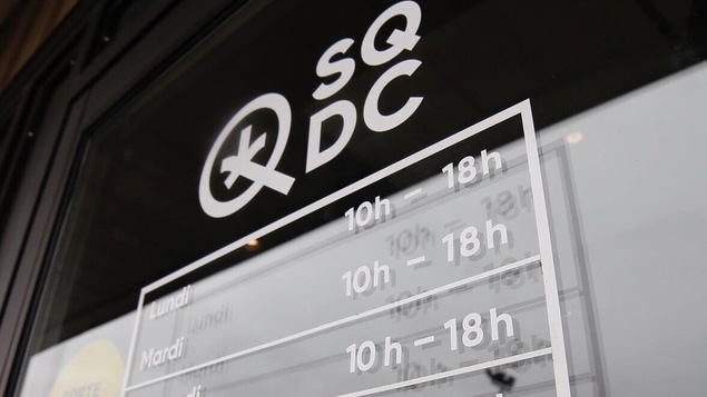 La porte d'une succursale de la SQDC, sur laquelle sont affichées les heures d'ouverture.