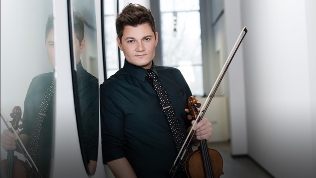 Le violoniste Alexandre Da Costa appuyé contre un mur sur lequel deux miroirs reflètent partiellement son visage