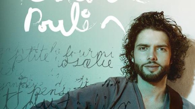 Alexandre Poulin regarde la caméra en face, une guitare à la main.