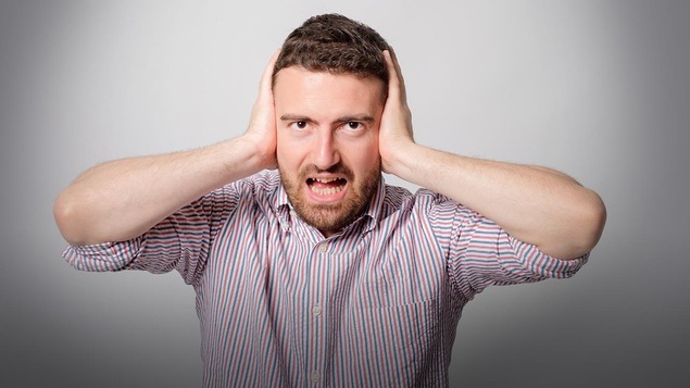 Une homme se bouche les oreilles