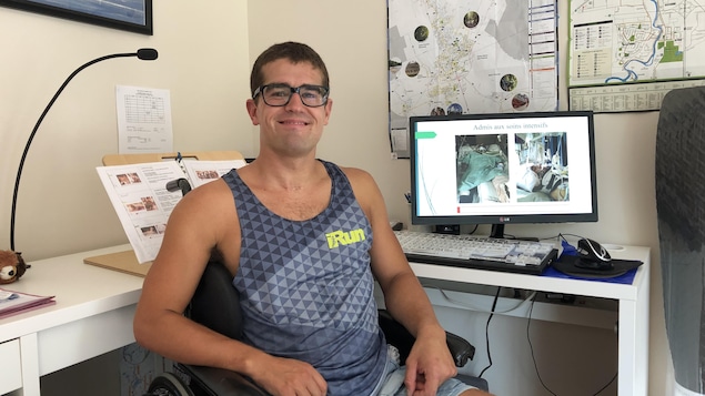 Un jeune homme souriant assis dans un fauteuil roulant.