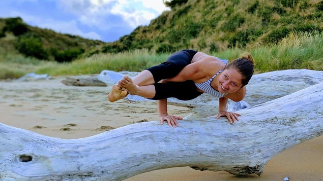 Andréann Duquet, faisant de l'acro-yoga sur un tronc d'arbre, sur une plage