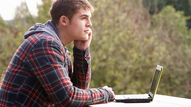 Un adolescent réfléchit devant son ordinateur