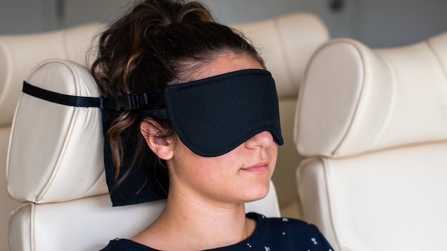 Une femme qui porte un masque pour dormir dans un avion