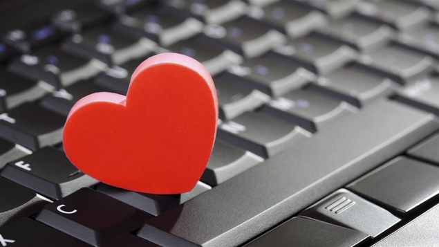 Un cœur rouge posé sur un clavier d'ordinateur.