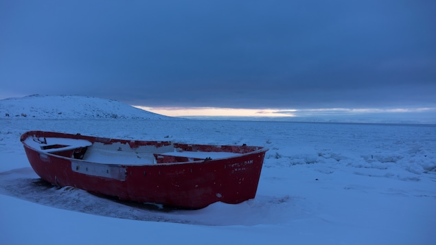 La coque d'un petit bateau pris dans la glace.