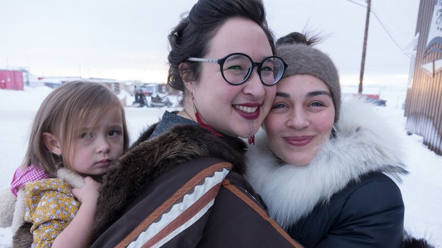 Deux femmes se serrent dans les bras, l'une d'entre elles portant une enfant dans son dos.