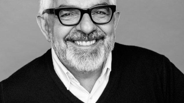 L'architecte Gilles Saucier avec des lunettes et un grand sourire.