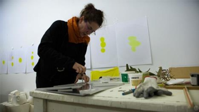 L'artiste en arts visuels, Hélène Rochette, travaille sur une oeuvre.