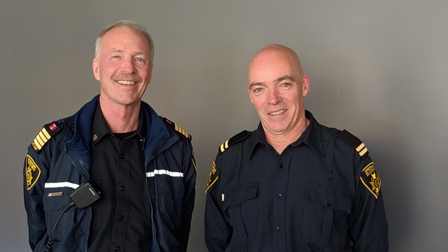 Deux pompiers, en uniforme dans le studio de Radio-Canada Sudbury.