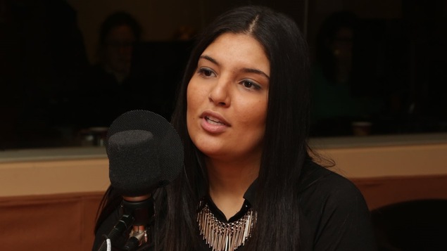 Aula Sabra derrière un micro dans un studio radio de Radio-Canada