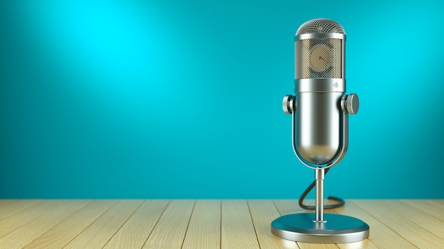 Un micro de radio posé sur un plancher devant un fond uni