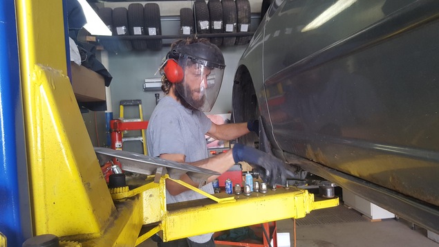 Un homme portant une visière en train de travailler sur la roue d'une voiture.