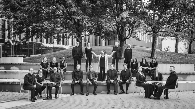 Une photo des choristes du Vancouver Cantata Singers assis sur des marches dans un parc