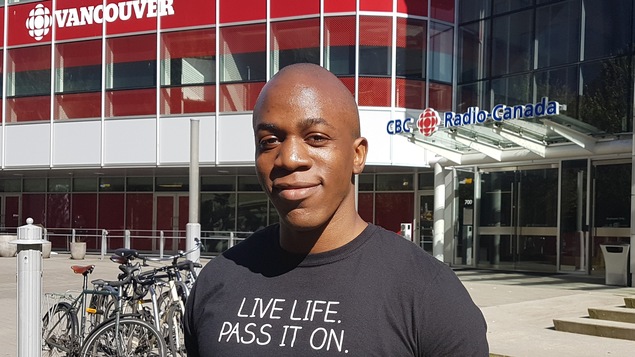 Jonny Kalambay de BC Transplant assis devant l'entrée des bureaux de Radio-Canada à Vancouver