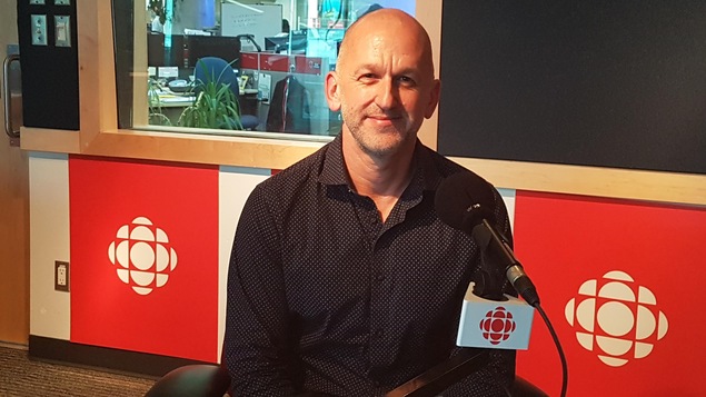 Le réalisateur du documentaire Franchir la ligne, Paul Emile d'Entremont derrière le micro dans un studio de Vancouver lors d'une entrevue radiophonique