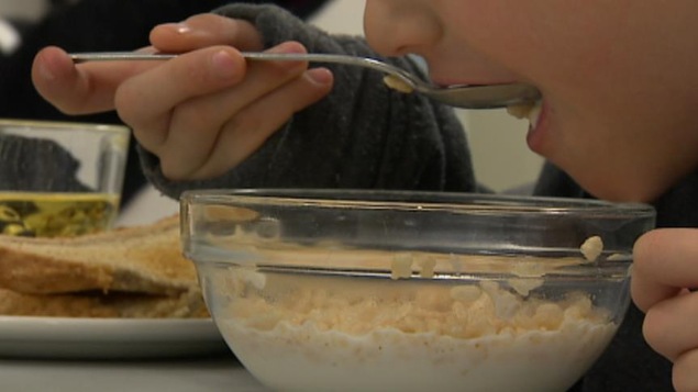 Un enfant se met une cuillière de céréale dans la bouche.