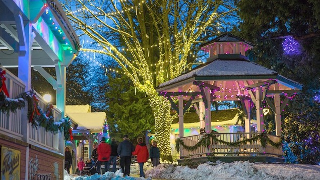Des guirlandes de couleurs dans les arbres et les bâtiments du Burnaby Village Museum