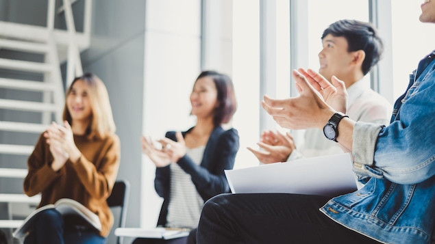 De jeunes employés d'entreprise applaudissent en souriant lors d'une réunion.