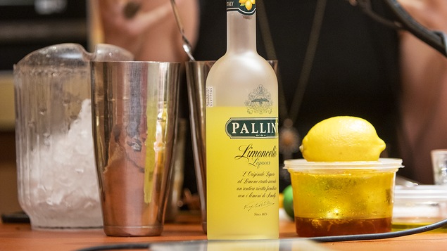 Des bouteilles d'alcool, un citron, un pichet de glace et autres préparations servant à faire des cocktails.
