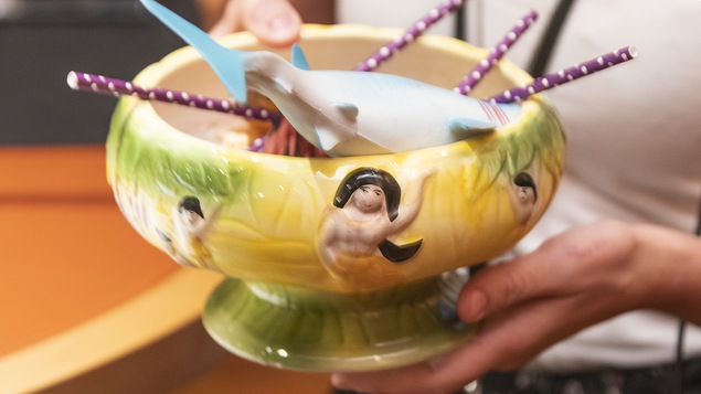 Un grand verre à cocktail de fantaisie orné d'un requin en caoutchouc et de pailles de papier.