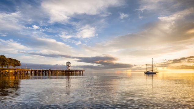 Vue sur un lac bordé d'un quai et sur lequel flotte un voilier de plaisance sur fond de lever de soleil à Port Angeles, dans l'État de Washington.