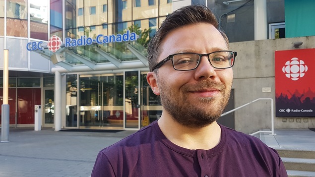 Un homme est posé plan taille devant l'immeuble de Radio-Canada.