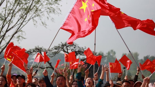 Photo d'une foule agitant des drapeaux chinois.