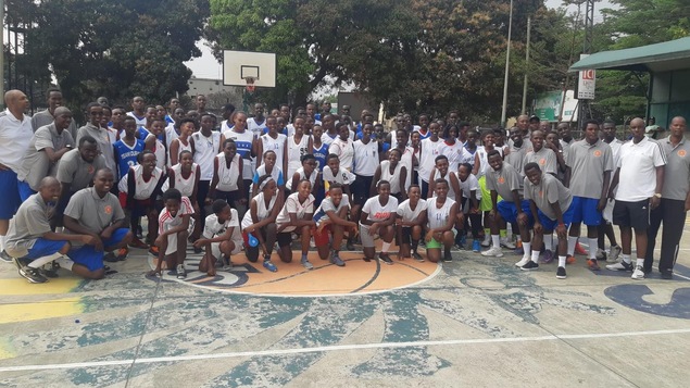 Un groupe de jeunes et d'adultes posant pour une photo sur un terrain de basketball