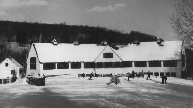Un long chalet blanc près d'une montagne.