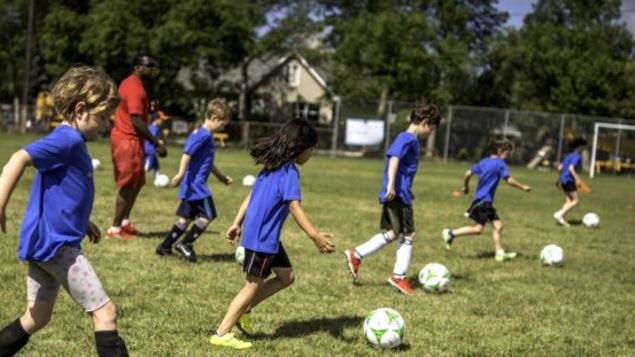 Des enfants tapent dans un ballon de soccer.