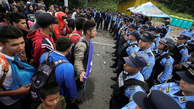 Des migrants en front d'un cordon policier.