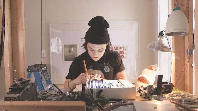 Une femme travaille une pellicule de film dans un petit studio.