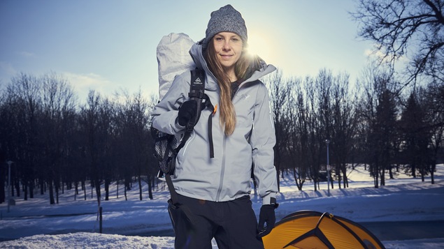 Caroline Côté pose devant sa tente, sac au dos, dans un parc.