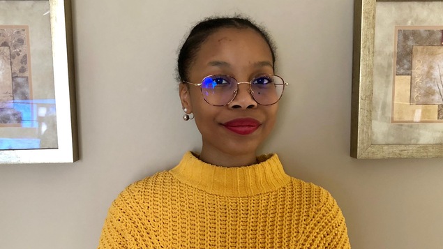 La jeune Nahida Mohamadou, 16 ans, sourit à la caméra, chez-elle.