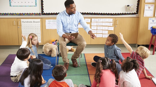 Des enfants du primaire posent des questions à leur enseignant.