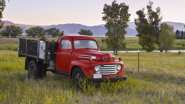 Un vieux camion rouge au coucher du soleil.