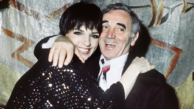 Liza Minnelli et Charles Aznavour dans les bras l'un de l'autre, souriant, regardant la caméra.