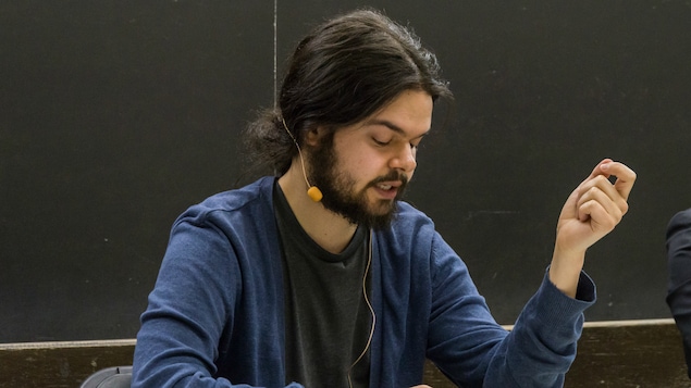 Nicolas Gaille en train de donner une conférence, assis derrière un bureau