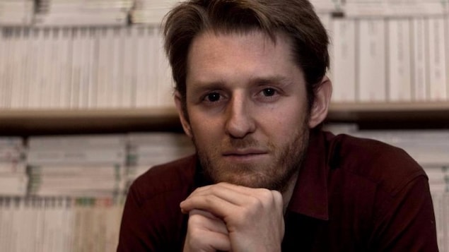 Alex Gagnon devant une étagère remplie de livres