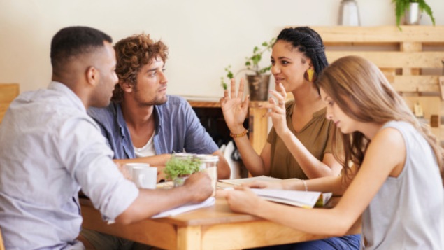 Quatre personnes discutent autour d'une table.
