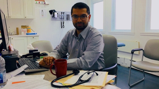 Un médecin assis à son bureau devant un écran d'ordinateur.