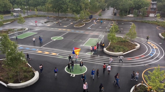 Une cour d'école parsemée d'îlots formés d'arbres.