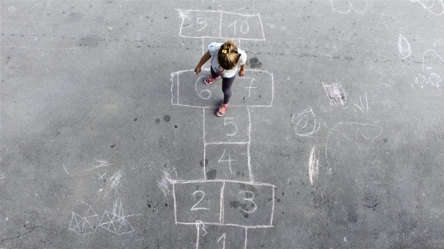 Une enfant joue à la marelle.