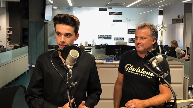 Philippe et André Thériault en studio à Radio-Canada Sudbury. Philippe a un paquet de cartes avec lui.