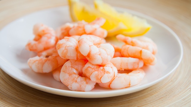 Une assiettes remplie de crevettes nordiques avec du citron
