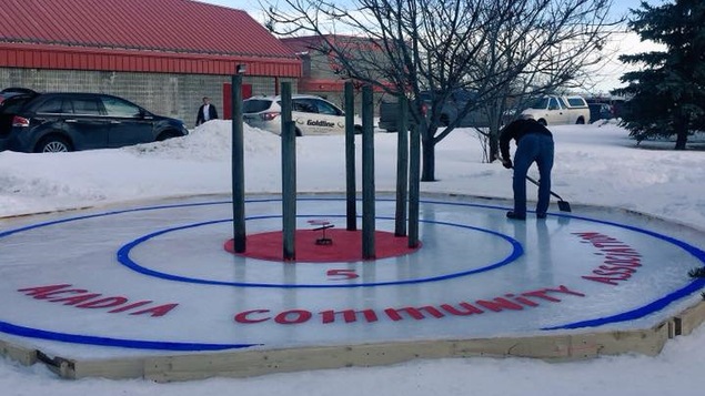 Un homme entretient une surface de crokicurl dans un parc enneigé