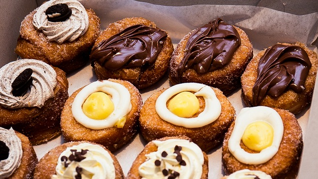 Beaucoup de crème, du sucre en poudre sur ces cronuts placés dans une boîte de carton.