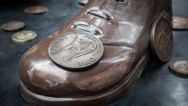 On voit une chaussure géante avec une pièce sur le dessus et d'autres pièces de monnaie autour.