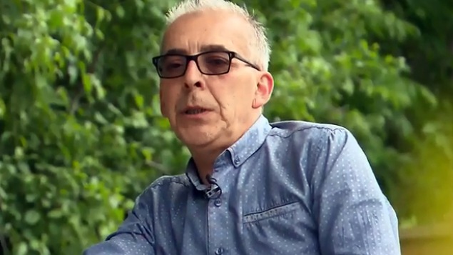 Un homme avec des lunettes noires est assis.